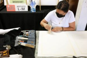 A person working with a piece of wall art at a Your Neighborhood Museum event